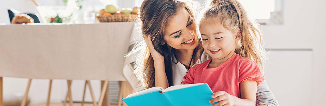 Mother and daughter in kitchen looking at a book