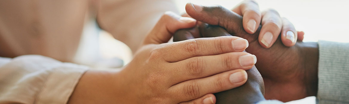 Hands of two people in a grasp. One set of hands is sandwiching the other.